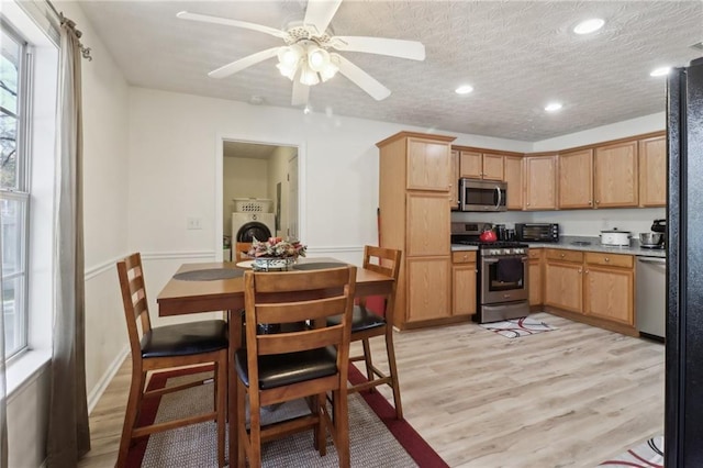 kitchen featuring a textured ceiling, appliances with stainless steel finishes, washer / dryer, and light wood-style floors