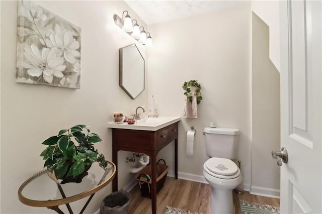 bathroom with vanity, wood finished floors, toilet, and baseboards