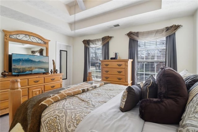 bedroom with visible vents and a raised ceiling