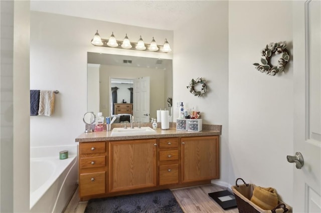 full bathroom with a garden tub, vanity, wood finished floors, and ensuite bathroom