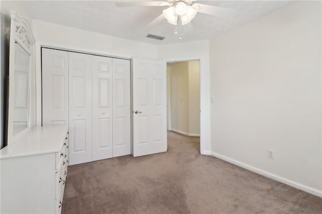 unfurnished bedroom featuring carpet, a closet, visible vents, a ceiling fan, and baseboards