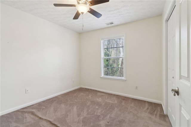 carpeted empty room with a ceiling fan, visible vents, baseboards, and a textured ceiling