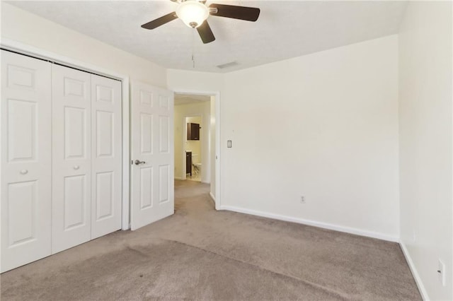 unfurnished bedroom with ceiling fan, a closet, baseboards, and carpet flooring