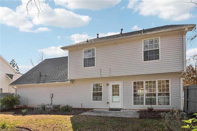 rear view of house with a shingled roof, a lawn, a patio, fence, and central air condition unit