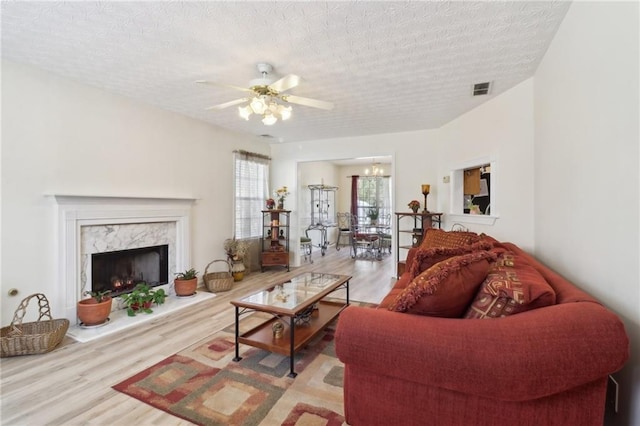 living area with a textured ceiling, a fireplace, visible vents, and wood finished floors