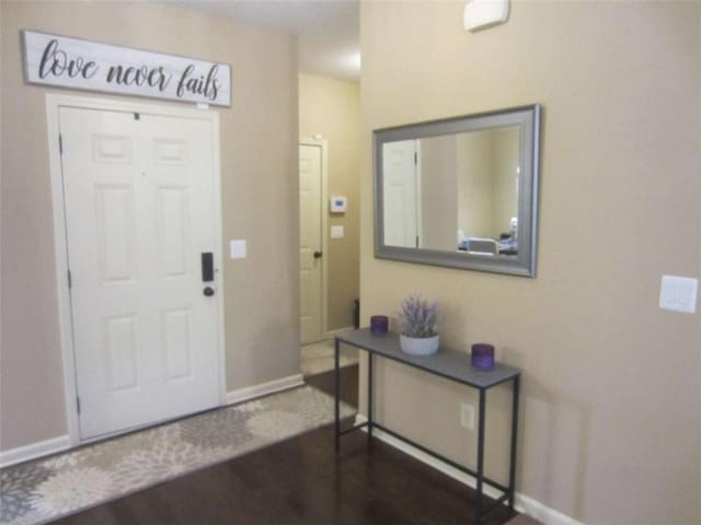 foyer featuring dark wood-style floors and baseboards