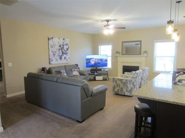 living area featuring a wealth of natural light, baseboards, a ceiling fan, and a fireplace