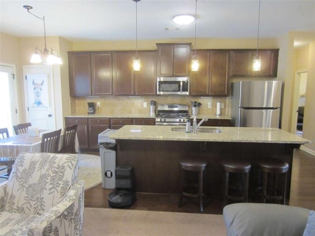 kitchen with tasteful backsplash, stainless steel appliances, a kitchen bar, and dark wood-style flooring