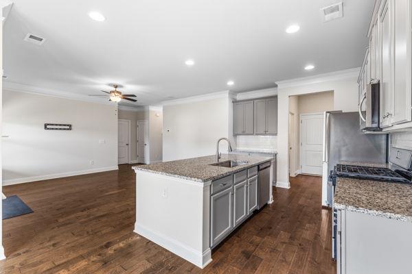 1494 Weeping Tree Cir, Auburn, GA 30548 - kitchen with gray cabinetry, crown molding, stainless steel appliances, an island with sink, and light stone countertops
