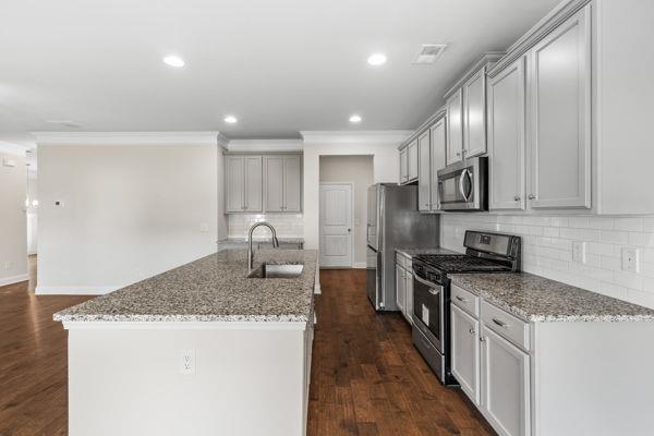 1494 Weeping Tree Cir, Auburn, GA 30548 - kitchen featuring stainless steel appliances, backsplash, a center island with sink, light stone counters, and crown molding