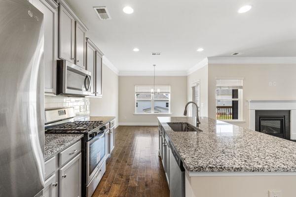 1494 Weeping Tree Cir, Auburn, GA 30548 - kitchen with appliances with stainless steel finishes, dark wood finished floors, light stone countertops, an island with sink, and recessed lighting