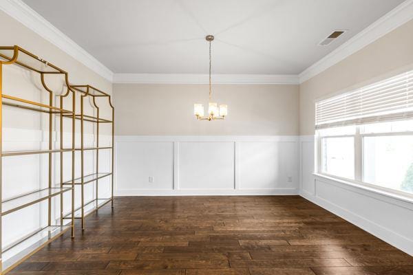1494 Weeping Tree Cir, Auburn, GA 30548 - unfurnished dining area with a chandelier, ornamental molding, hardwood / wood-style floors, wainscoting, and a decorative wall