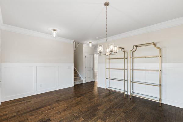 1494 Weeping Tree Cir, Auburn, GA 30548 - unfurnished room featuring crown molding, stairs, wainscoting, a chandelier, and dark wood-style floors