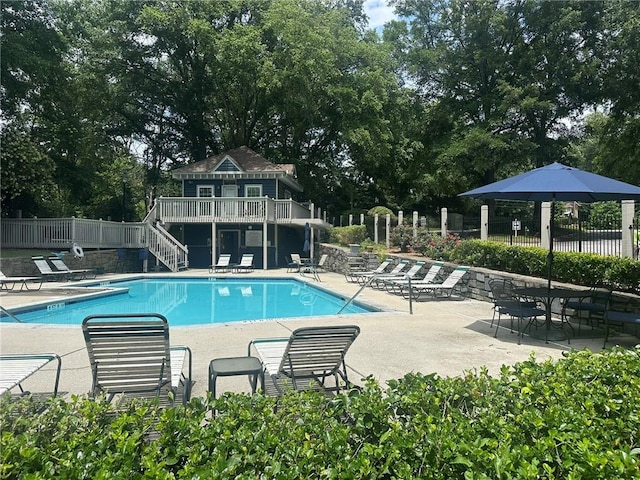 1384 N Crossing Dr NE, Atlanta, GA 30329 - community pool featuring stairs, a wooden deck, a patio, and view of wooded area