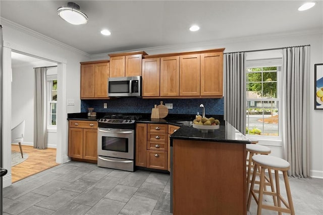 1384 N Crossing Dr NE, Atlanta, GA 30329 - kitchen featuring appliances with stainless steel finishes, ornamental molding, a kitchen bar, decorative backsplash, and brown cabinetry