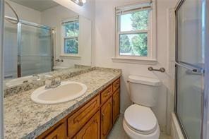 full bath featuring toilet, vanity, and a shower with shower door