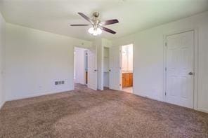 unfurnished bedroom with ceiling fan, carpet flooring, and connected bathroom