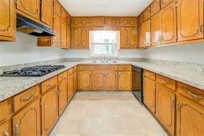 kitchen with brown cabinetry, under cabinet range hood, light countertops, black appliances, and a sink