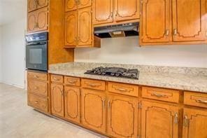 kitchen with brown cabinetry, gas cooktop, oven, and under cabinet range hood