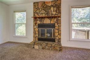 carpeted living room with baseboards and a stone fireplace