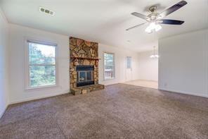 unfurnished living room featuring carpet, a fireplace, visible vents, and ceiling fan