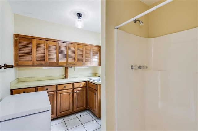 kitchen featuring brown cabinets, light countertops, a sink, and light tile patterned flooring