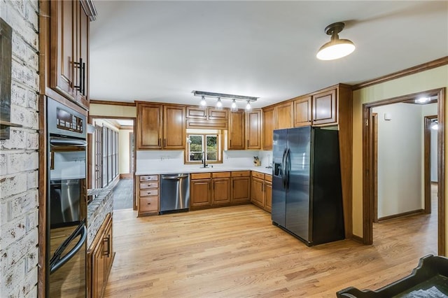 kitchen featuring black appliances, a sink, light wood-style flooring, and brown cabinets