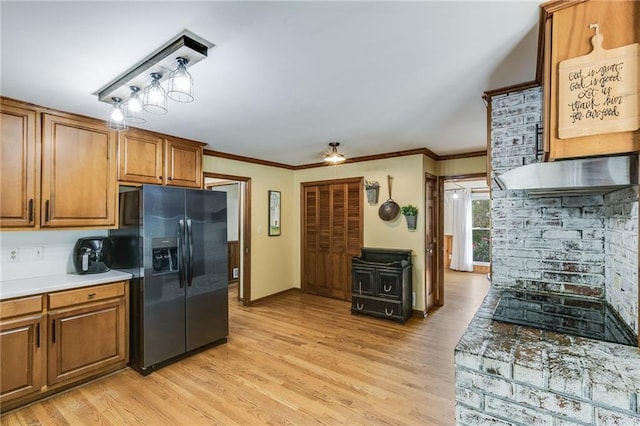 kitchen featuring baseboards, light wood-style floors, ornamental molding, black fridge, and brown cabinetry