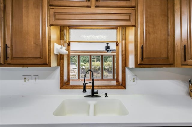 kitchen featuring brown cabinetry, light countertops, and a sink