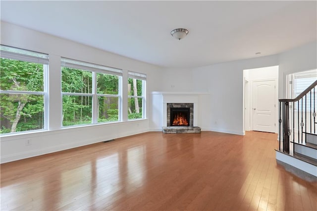 unfurnished living room with a stone fireplace, a healthy amount of sunlight, and light hardwood / wood-style floors