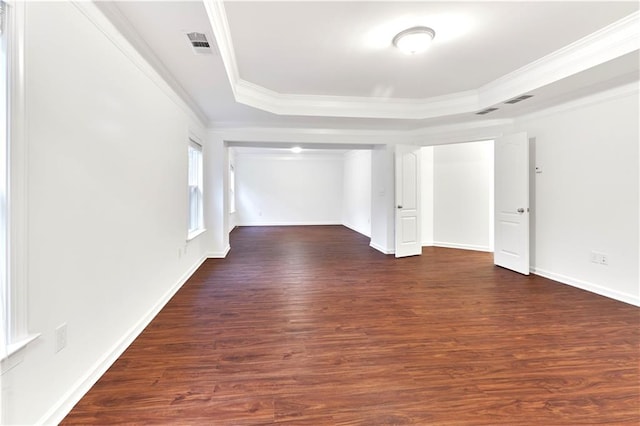 unfurnished room with a raised ceiling, dark hardwood / wood-style floors, and ornamental molding