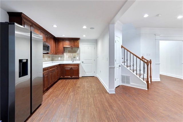 kitchen with ornamental molding, wood-type flooring, stainless steel appliances, and tasteful backsplash