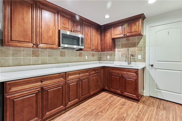 kitchen featuring light wood-type flooring, tasteful backsplash, and sink