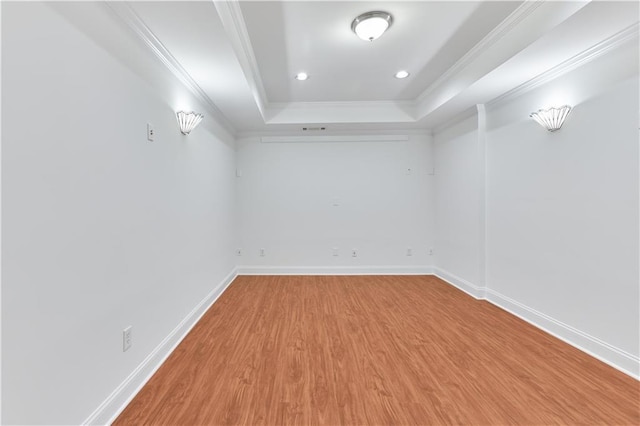 spare room with light hardwood / wood-style floors, a raised ceiling, and crown molding