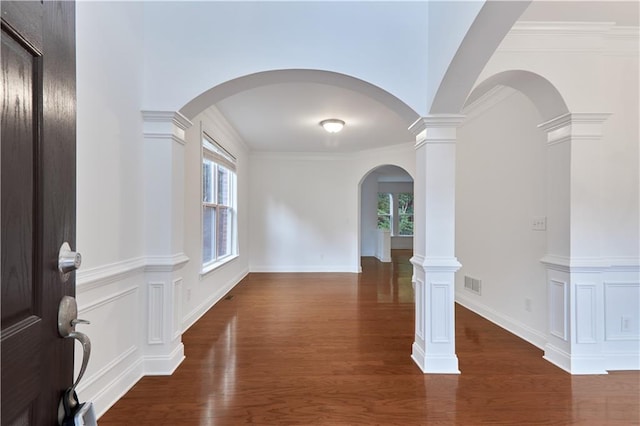 interior space featuring ornate columns, crown molding, and dark wood-type flooring