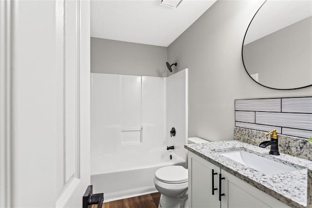bathroom featuring toilet, wood finished floors, vanity, and shower / bathtub combination