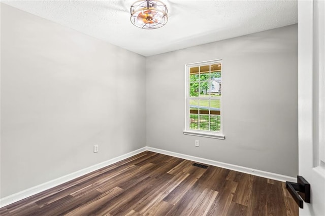 unfurnished room with dark wood-type flooring, baseboards, and a textured ceiling