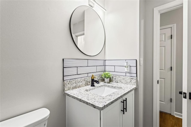 bathroom featuring toilet, vanity, and wood finished floors