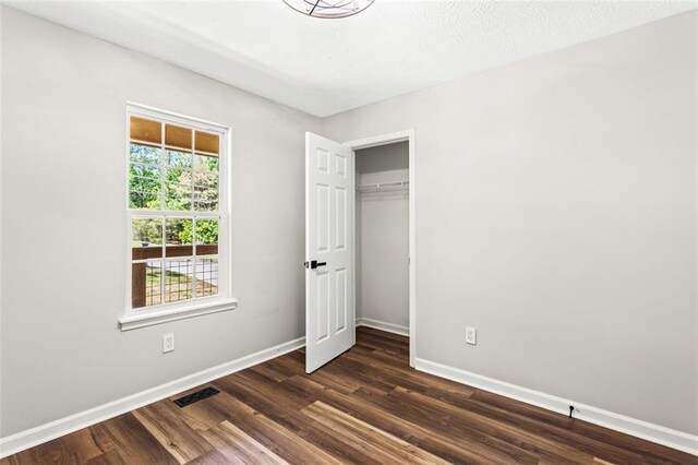 unfurnished bedroom with baseboards, dark wood-style floors, and a closet