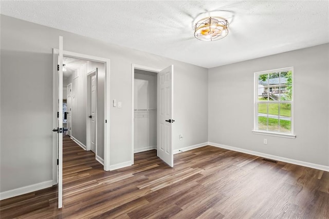 unfurnished bedroom featuring wood finished floors, a closet, baseboards, and a textured ceiling