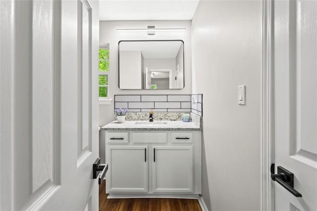 bathroom with tasteful backsplash, wood finished floors, and vanity