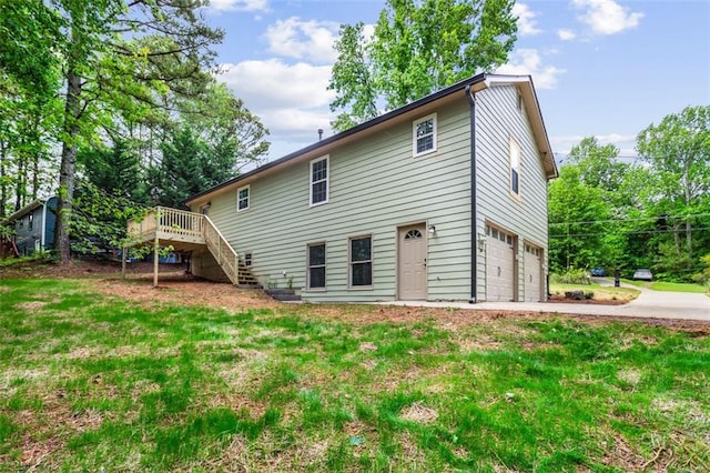 rear view of house featuring stairs, an attached garage, a deck, driveway, and a yard