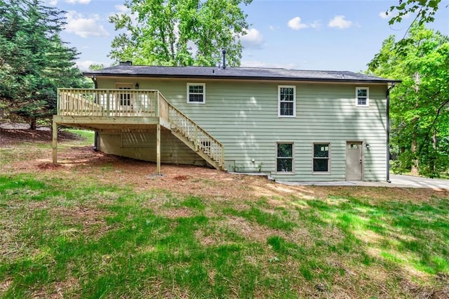 rear view of property featuring stairs, a wooden deck, a lawn, and a patio