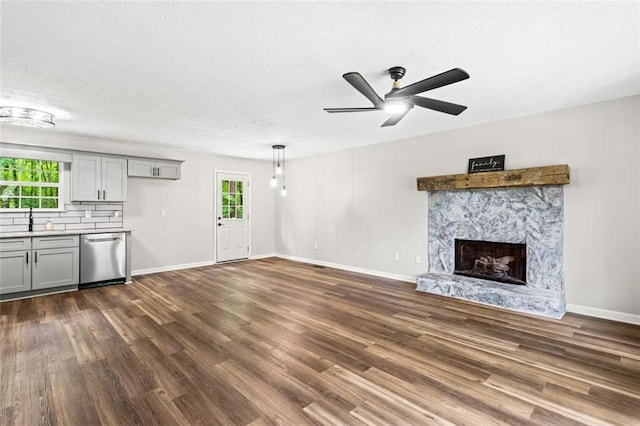 unfurnished living room with dark wood-type flooring, healthy amount of natural light, ceiling fan, and a textured ceiling