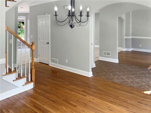 unfurnished dining area featuring crown molding, dark hardwood / wood-style flooring, and an inviting chandelier