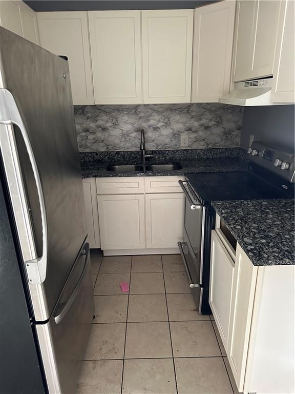 kitchen featuring sink, light tile patterned floors, stainless steel fridge, electric stove, and white cabinets