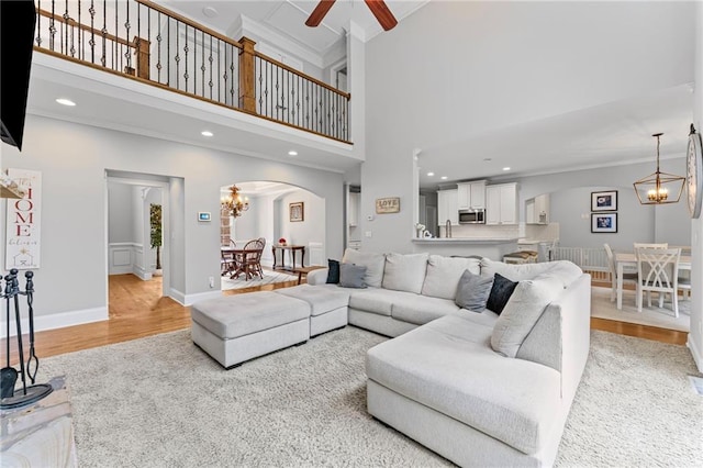 3560 Greenside Ct, Dacula, GA 30019 - living room with arched walkways, a chandelier, light wood-style flooring, a towering ceiling, and crown molding
