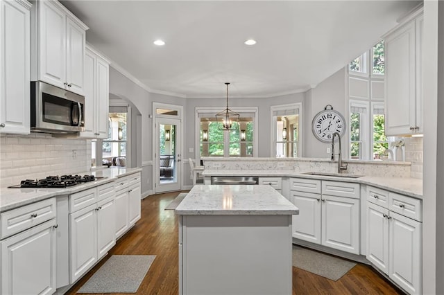3560 Greenside Ct, Dacula, GA 30019 - kitchen featuring appliances with stainless steel finishes, a peninsula, white cabinetry, decorative backsplash, and arched walkways