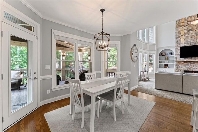 3560 Greenside Ct, Dacula, GA 30019 - dining space with a chandelier, built in features, dark wood finished floors, ornamental molding, and a stone fireplace