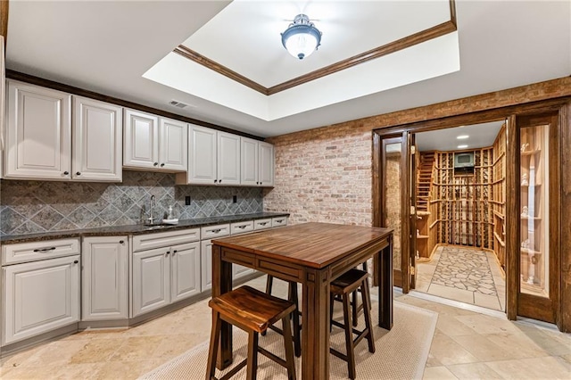 3560 Greenside Ct, Dacula, GA 30019 - kitchen with dark countertops, decorative backsplash, white cabinetry, crown molding, and a raised ceiling